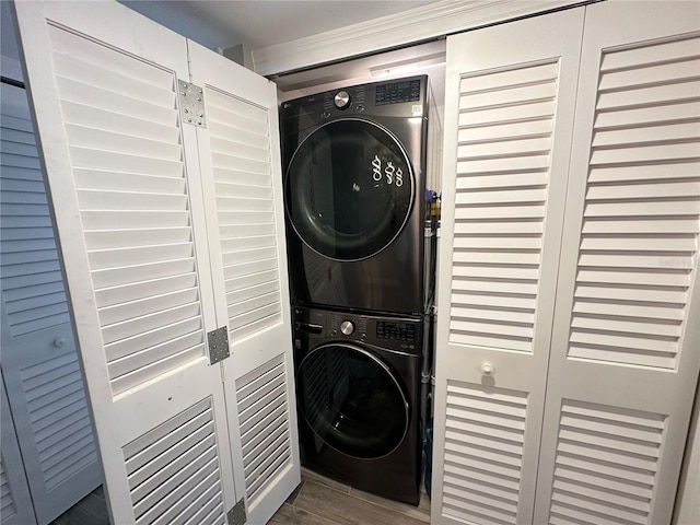 clothes washing area with stacked washing maching and dryer and dark hardwood / wood-style flooring