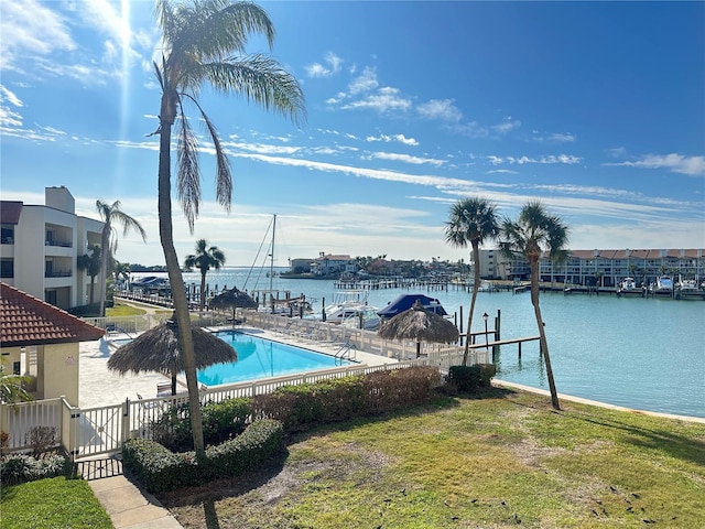 view of swimming pool with a water view and a lawn