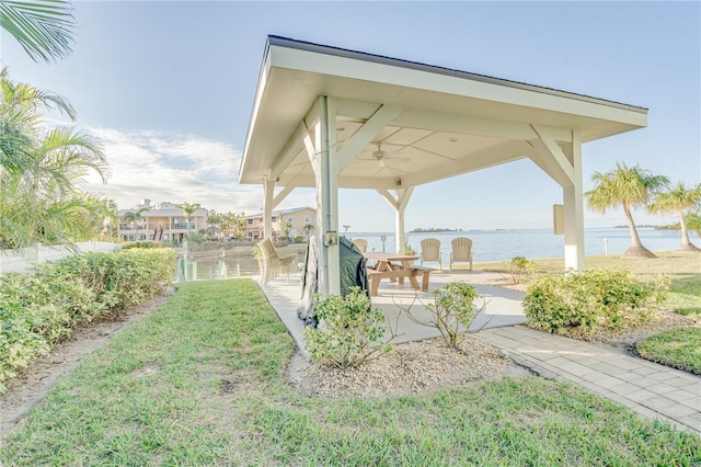 view of yard featuring ceiling fan, a water view, a gazebo, and a patio area