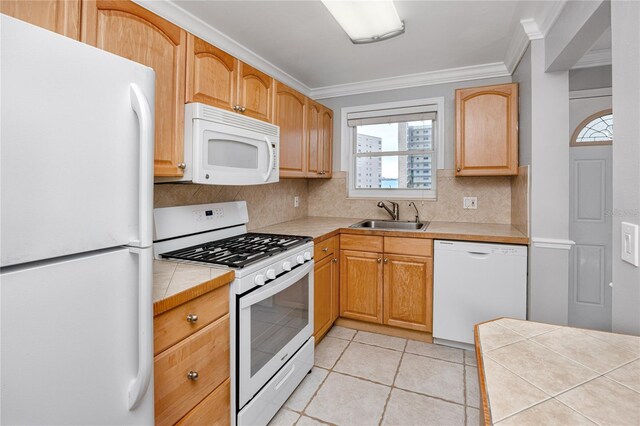 kitchen with sink, white appliances, light tile patterned floors, and tile counters