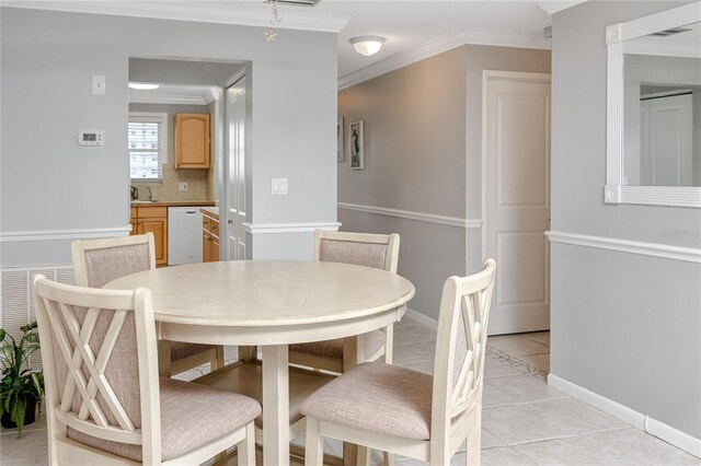 tiled dining space featuring sink and crown molding