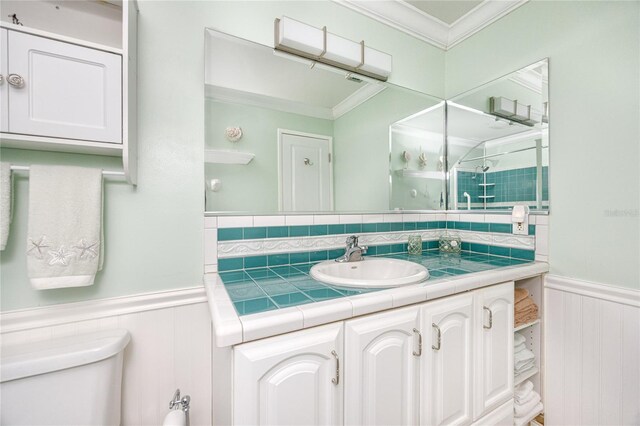 bathroom with toilet, vanity, an enclosed shower, and crown molding