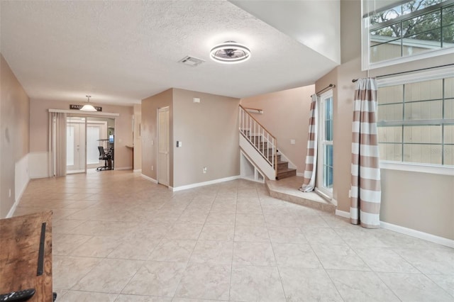 unfurnished living room featuring light tile patterned floors and a textured ceiling