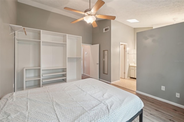 bedroom featuring a textured ceiling, lofted ceiling, hardwood / wood-style flooring, a closet, and ceiling fan