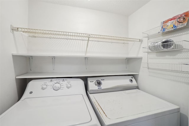 clothes washing area with a textured ceiling and washer and clothes dryer