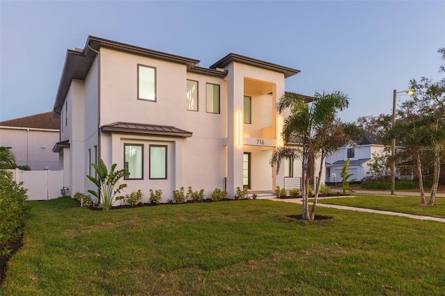 view of front of house with a balcony and a front lawn