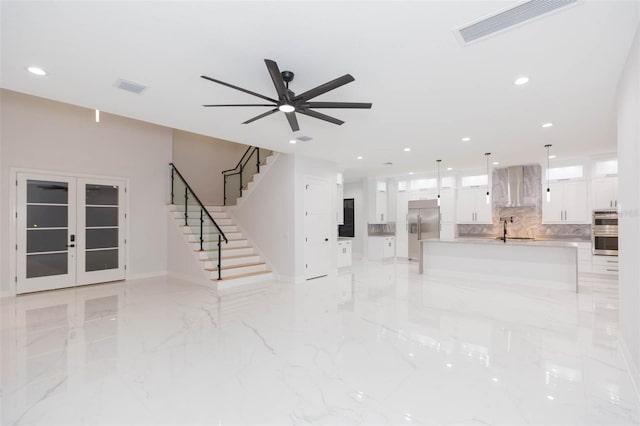 unfurnished living room featuring ceiling fan, french doors, and sink