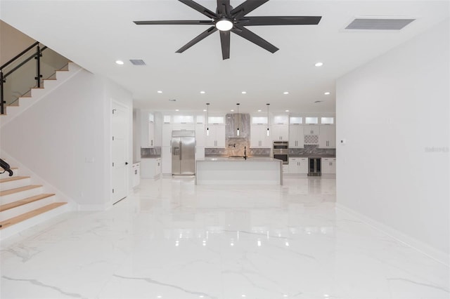 unfurnished living room featuring sink, ceiling fan, and beverage cooler