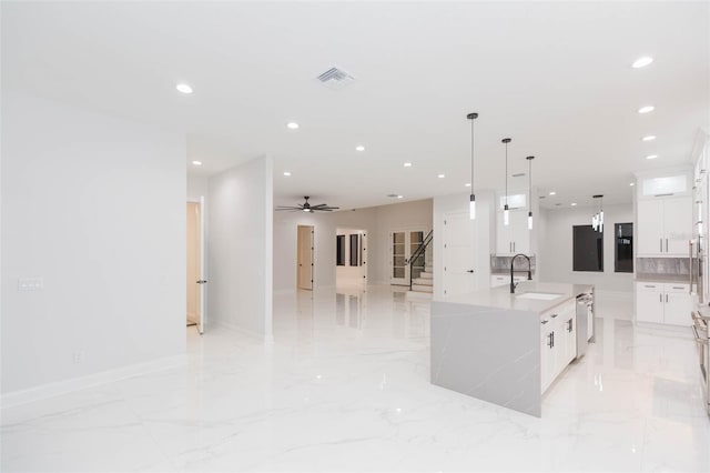 kitchen with pendant lighting, a spacious island, white cabinets, ceiling fan, and sink