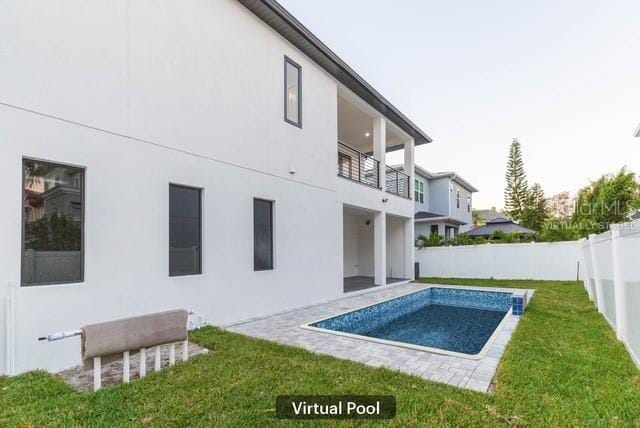 rear view of house featuring a balcony, a yard, a fenced in pool, and a patio area