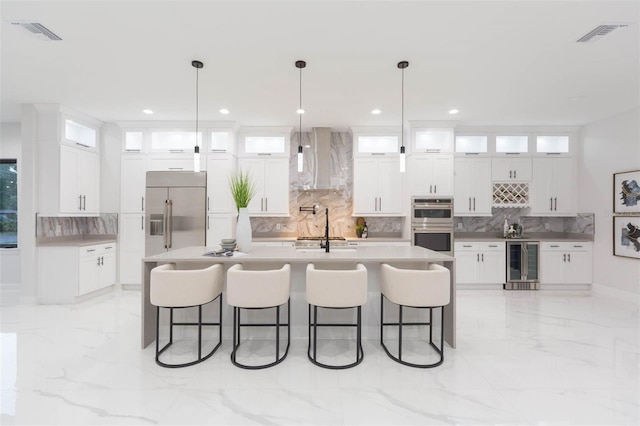 716 S Lois Ave, Tampa, FL 33609 - kitchen featuring appliances with stainless steel finishes, wall chimney exhaust hood, wine cooler, decorative backsplash, and light marble finish floors