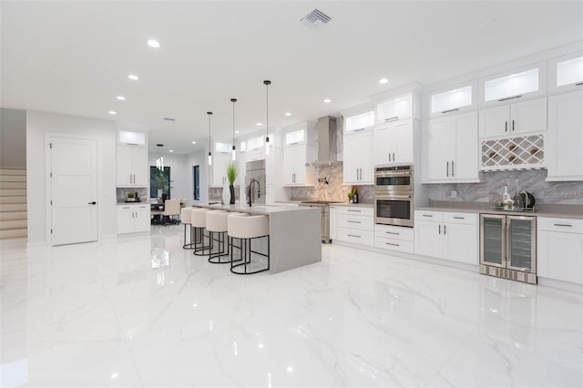 716 S Lois Ave, Tampa, FL 33609 - kitchen with wine cooler, wall chimney exhaust hood, stainless steel double oven, backsplash, and recessed lighting
