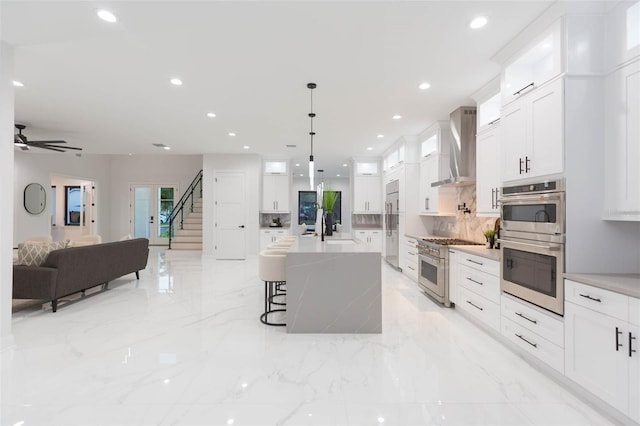 716 S Lois Ave, Tampa, FL 33609 - kitchen with wall chimney exhaust hood, premium appliances, open floor plan, backsplash, and a breakfast bar