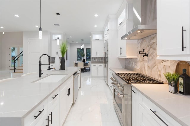 716 S Lois Ave, Tampa, FL 33609 - kitchen featuring premium appliances, wall chimney exhaust hood, a sink, tasteful backsplash, and white cabinetry