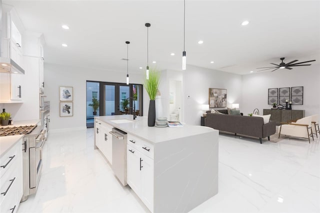 716 S Lois Ave, Tampa, FL 33609 - kitchen featuring a sink, light marble finish floors, stainless steel appliances, an island with sink, and white cabinets