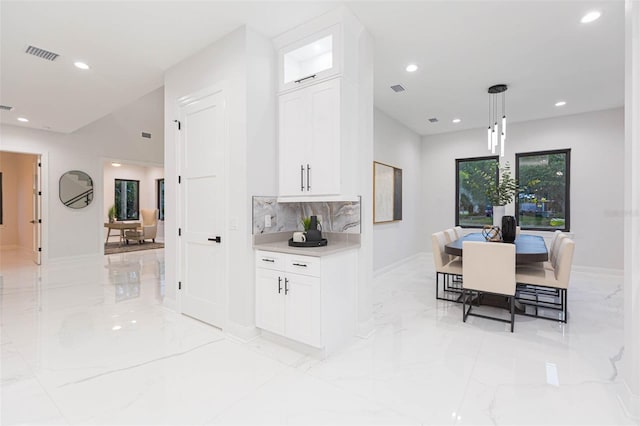 716 S Lois Ave, Tampa, FL 33609 - kitchen with light marble finish flooring, recessed lighting, tasteful backsplash, light countertops, and white cabinetry