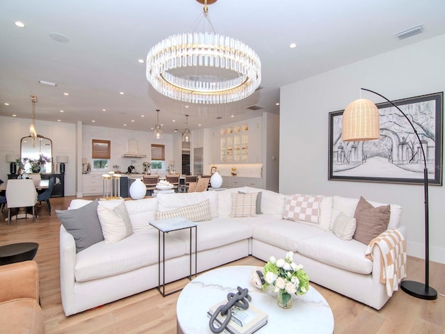 living room with light hardwood / wood-style floors and a notable chandelier