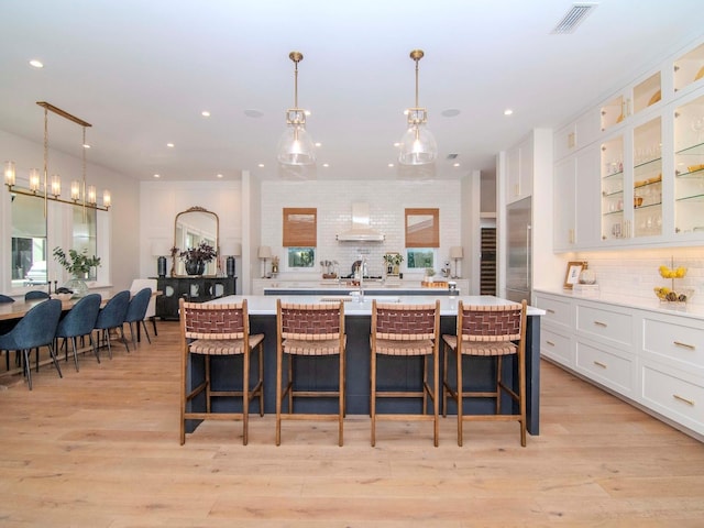 kitchen with a kitchen bar, decorative light fixtures, white cabinets, and tasteful backsplash