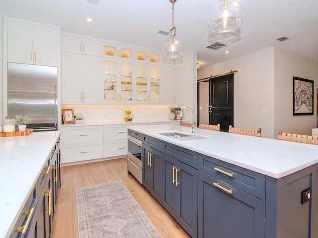 kitchen featuring built in refrigerator, white cabinets, and sink