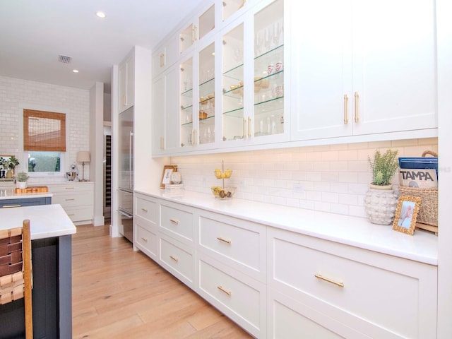 kitchen with backsplash, white cabinets, and light wood-type flooring