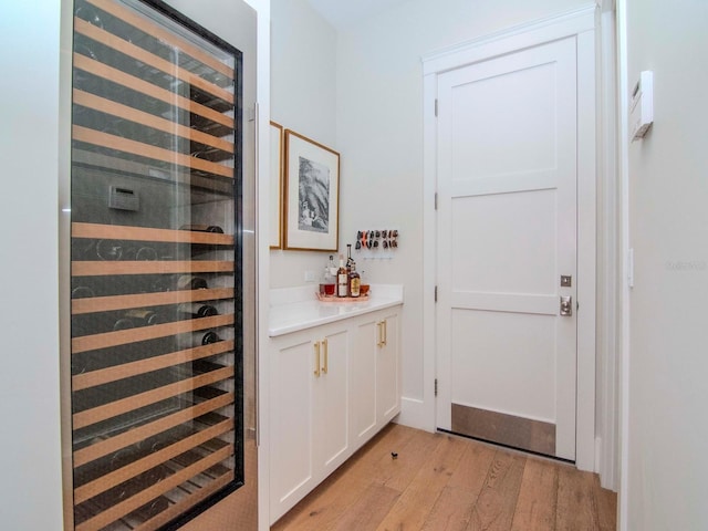 bar featuring white cabinetry, light hardwood / wood-style flooring, and wine cooler