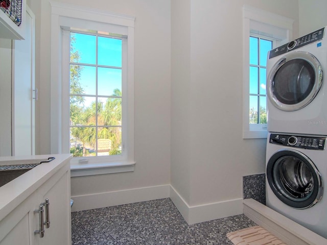 laundry area featuring stacked washer and dryer and cabinets