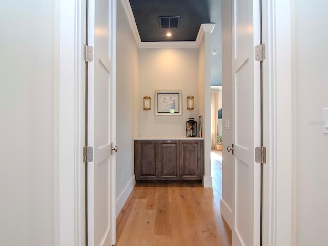 hallway with light hardwood / wood-style floors and ornamental molding