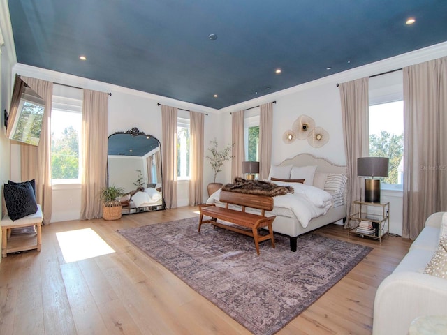 bedroom with multiple windows, light hardwood / wood-style flooring, and crown molding