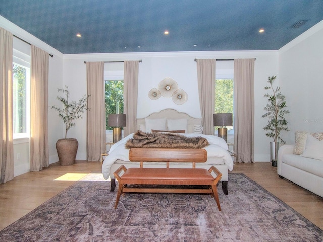 bedroom featuring crown molding, light hardwood / wood-style flooring, and multiple windows