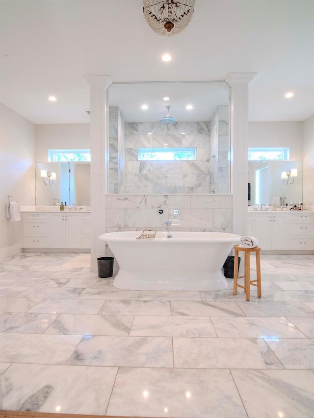 bathroom with a tub to relax in, a healthy amount of sunlight, and vanity