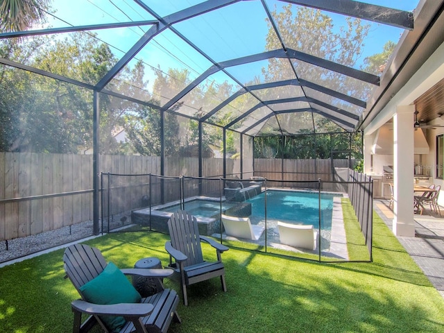 view of swimming pool featuring glass enclosure, exterior kitchen, a patio area, an in ground hot tub, and a yard