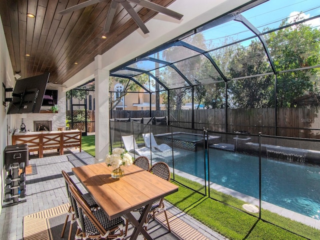 view of swimming pool with a patio area, a lanai, a large fireplace, and an in ground hot tub