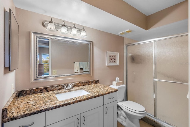 bathroom featuring toilet, vanity, and a shower with shower door