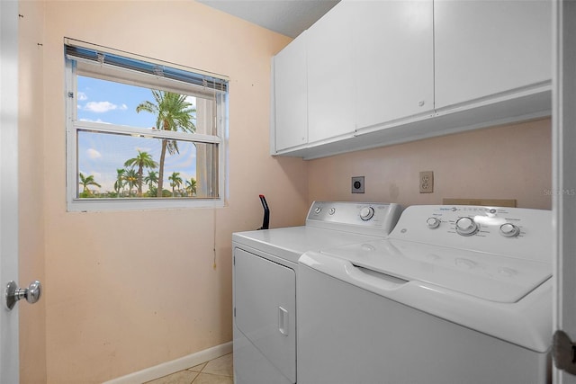 laundry room featuring washer and dryer, cabinets, and light tile patterned floors