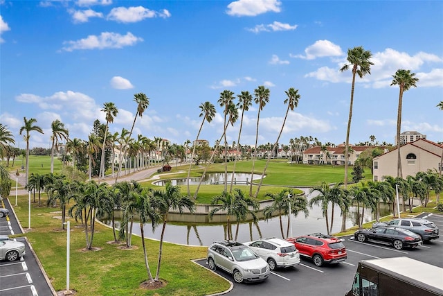 view of vehicle parking featuring a water view and a lawn