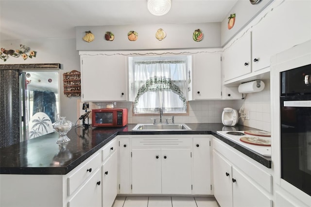 kitchen with tasteful backsplash, sink, light tile patterned floors, and white cabinets