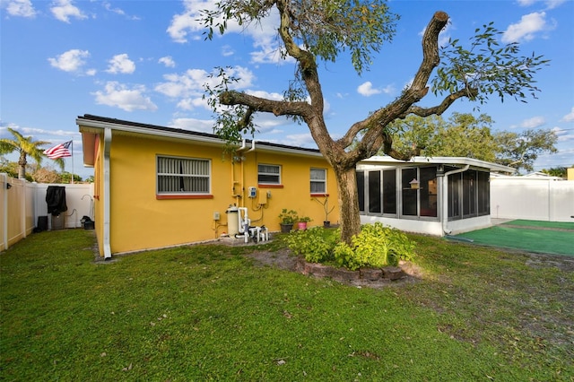 rear view of property with a yard and a sunroom