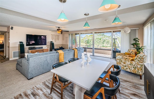 dining room featuring ceiling fan, light colored carpet, and a textured ceiling