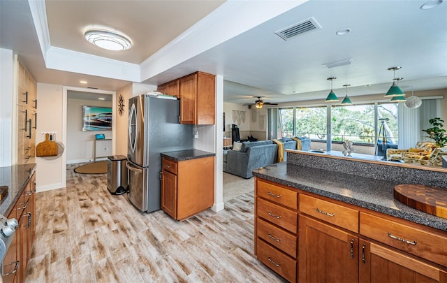 kitchen with a raised ceiling, ceiling fan, light wood-type flooring, stainless steel refrigerator, and pendant lighting