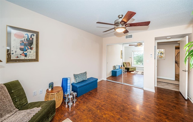 sitting room featuring a textured ceiling, ceiling fan, and dark wood-type flooring