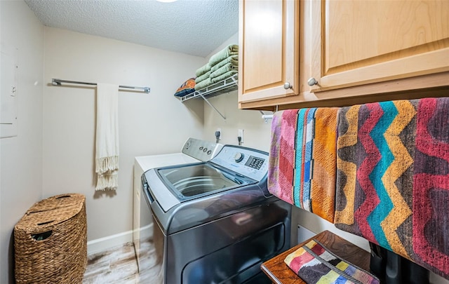 laundry area with independent washer and dryer, a textured ceiling, cabinets, and light wood-type flooring