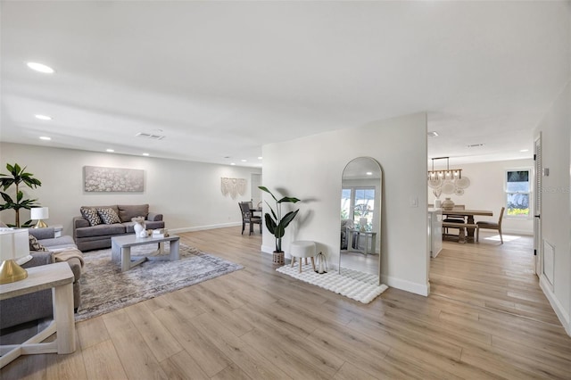 living room featuring light hardwood / wood-style floors, a chandelier, and plenty of natural light