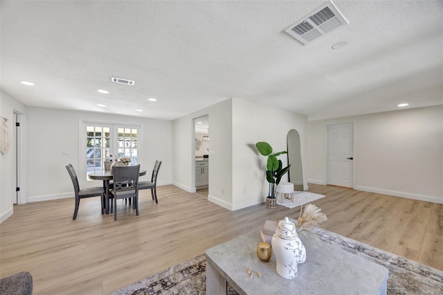 dining space featuring french doors, a textured ceiling, and light wood-type flooring