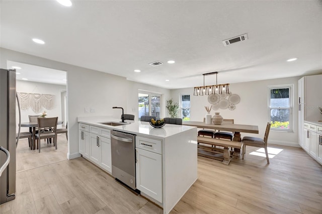 kitchen featuring pendant lighting, stainless steel appliances, light hardwood / wood-style floors, white cabinets, and sink