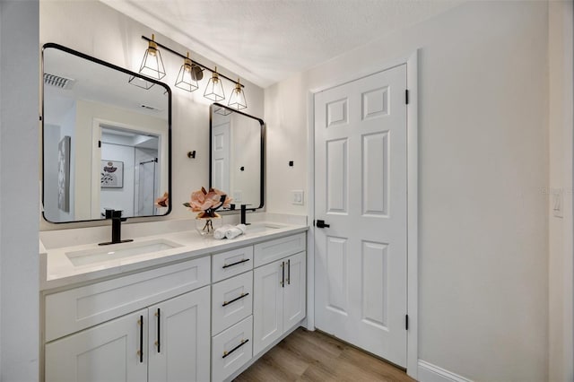 bathroom with a textured ceiling, vanity, and wood-type flooring