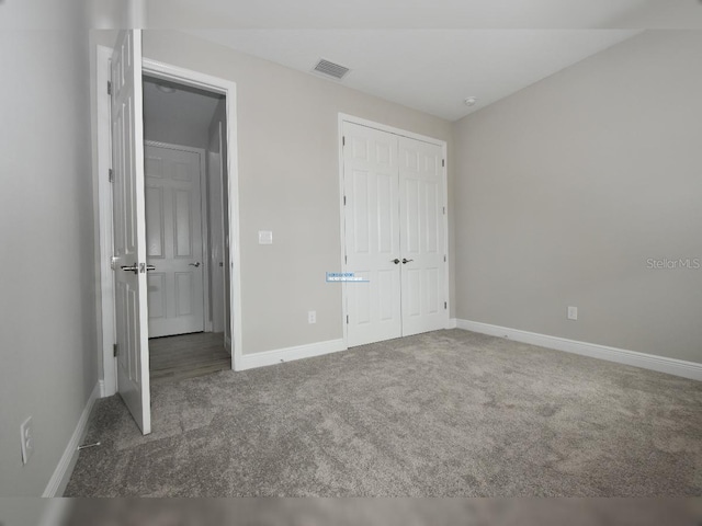 unfurnished bedroom featuring a closet and dark carpet