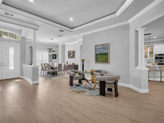 living room featuring a tray ceiling, ornamental molding, and ornate columns