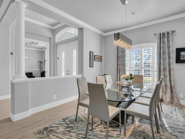 dining space featuring light wood-type flooring, ornate columns, and ornamental molding