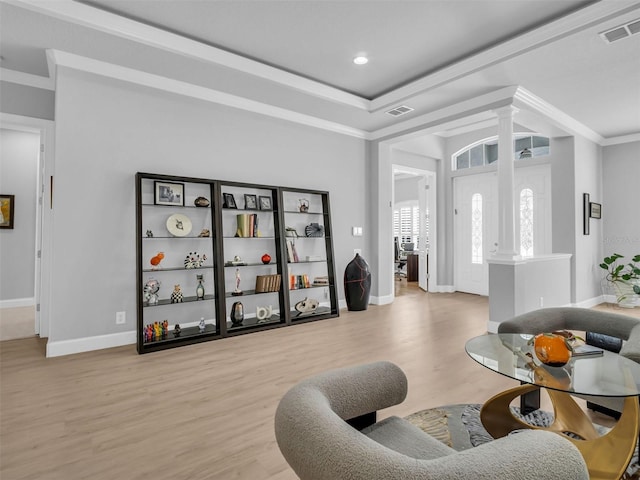 interior space featuring ornamental molding, light hardwood / wood-style flooring, and ornate columns