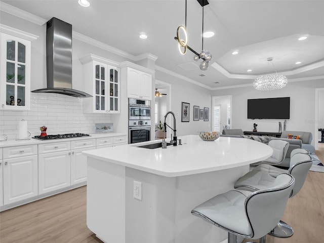 kitchen with wall chimney exhaust hood, white cabinetry, double oven, sink, and gas stovetop